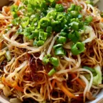 Easy Chow Mein Recipe: Better-Than-Takeout Stir-Fried Noodles Overhead view of a ceramic bowl filled with glossy amber chow mein noodles and julienned carrots. (Easy Chow Mein Recipe)