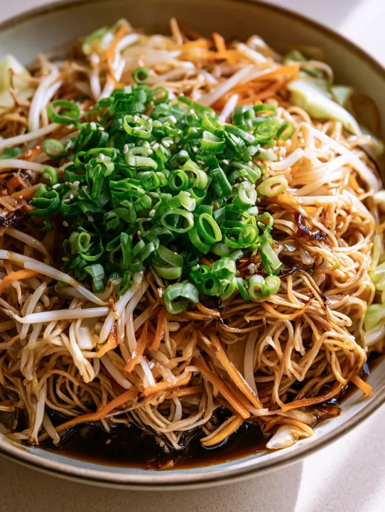 Close-up of chow mein noodles with visible bean sprouts and green onion garnish. (Easy Chow Mein Recipe)