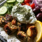 Close up view of seared cubed chicken with dark golden-brown char marks in a Mediterranean Chicken Meal Prep bowl.