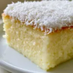Brazilian Coconut Custard Cake: The Ultimate Creamy Flourless Dessert Close up of a Brazilian Coconut Custard Cake slice showing the moist, glistening ivory texture and no air bubbles. (Brazilian Coconut Custard Cake)