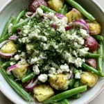 Mediterranean Greek Potato Salad with Zesty Lemon Vinaigrette A rustic white ceramic bowl filled with Mediterranean Greek Potato Salad featuring red-skinned potatoes and bright green beans. (Mediterranean Greek Potato Salad)