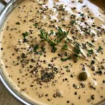 Creamy Peppercorn Sauce: The Ultimate Guide to a Glossy Restaurant-Quality Reduction Close-up of Creamy Peppercorn Sauce speckled with coarse black pepper and green peppercorns in a skillet.