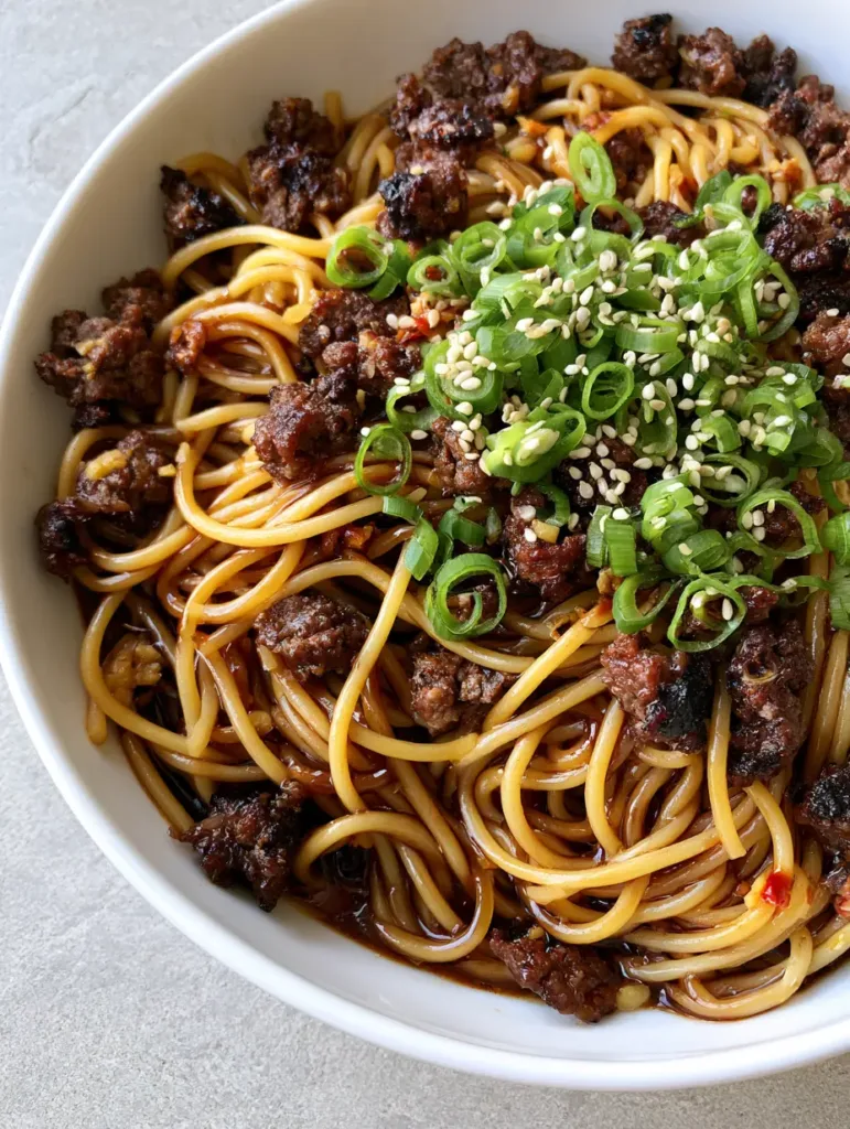 Top-down view of Asian Ground Beef Spaghetti showing the dark, translucent soy sauce and red chili oil flecks. (Asian Ground Beef Spaghetti)