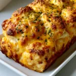 Close-up of golden-brown biscuit mounds baked into a loaf with melted sharp cheddar. (Red Lobster Cheddar Bay Biscuit Loaf)