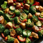 Close-up of seared chicken breast cubes and vibrant green broccoli in a shimmering savory sauce. (Chicken and Vegetable Skillet)