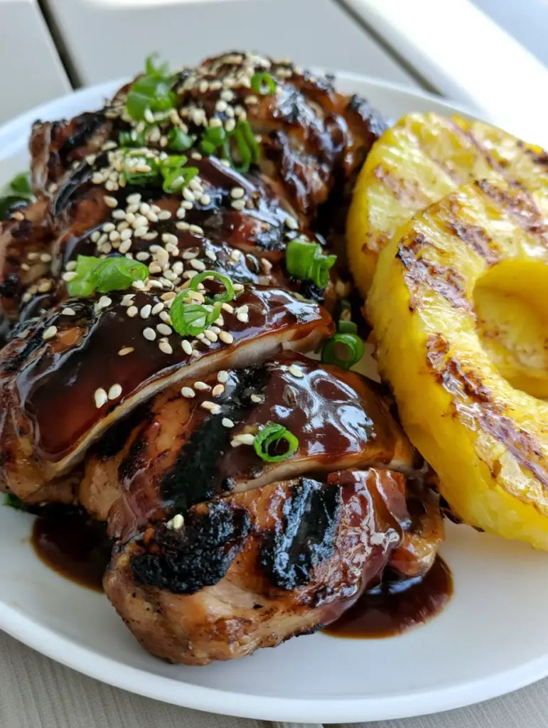 Hawaiian Teriyaki Chicken: The Ultimate Sticky, Char-Grilled Island Feast 2 Slices of grilled chicken thighs showing charred grill marks and vibrant green onion garnish.