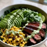 Handheld photo of a Whole30 Steak and Avocado Bowl in a matte white ceramic dish showing charred corn and medium-rare steak.