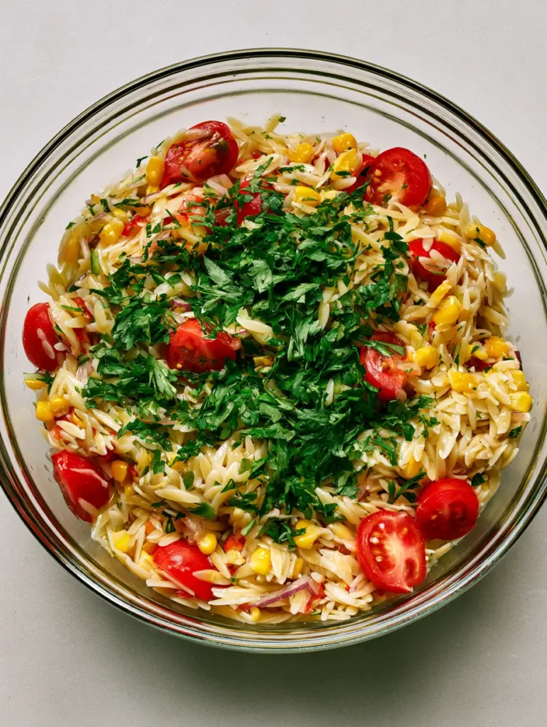 Close up of a fresh herb vinaigrette dressing on an orzo pasta salad. (Cold BBQ Side Dishes)