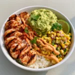 Close up photo of a Grilled Shrimp Bowl showing the thick pale orange dressing drizzled over six large shrimp and chunky avocado. (Grilled Shrimp Bowl)