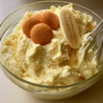 Banana Pudding Frosting: The Ultimate Fluffy Southern-Inspired Recipe Thick, pale-yellow banana pudding frosting with soft peaks and a metal whisk in a glass bowl. (Banana Pudding Frosting)