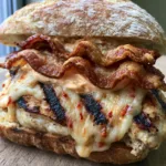Close-up of a Grilled Chicken Bacon Ciabatta showing thick-cut chicken with dark diagonal char marks and oozing cheese.
