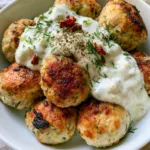 Mediterranean Chicken Meatballs with Creamy Tzatziki and Sun-Dried Tomatoes Close-up of seared Mediterranean Chicken Meatballs with charred edges and green herb flecks in a ceramic bowl.