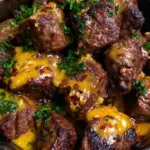 Cowboy Butter Steak Bites with Garlic Herb Skillet Char Close-up shot of seared beef steak cubes with a caramelized crust and glossy yellow-orange butter sauce flecked with red chili and garlic.