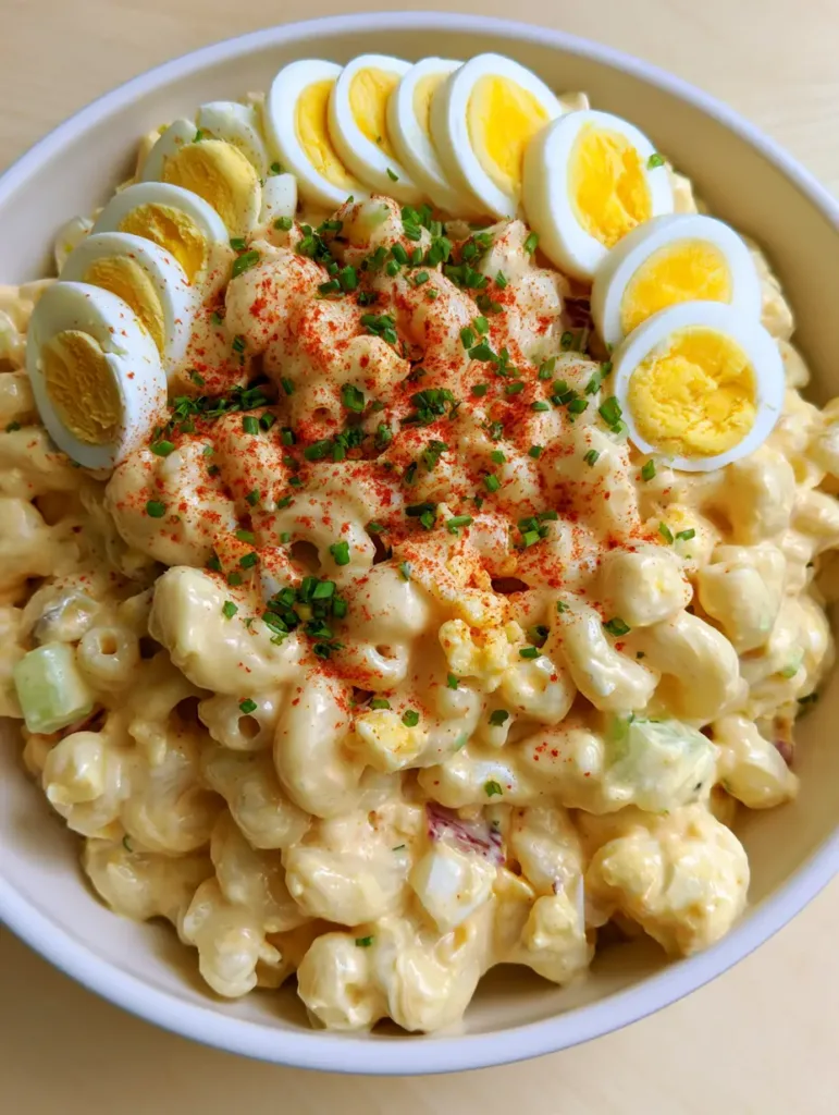 Deviled Egg Macaroni Salad: The Ultimate Creamy Potluck Classic 2 Top-down view of the garnished Deviled Egg Macaroni Salad with neatly arranged egg slices and chives.