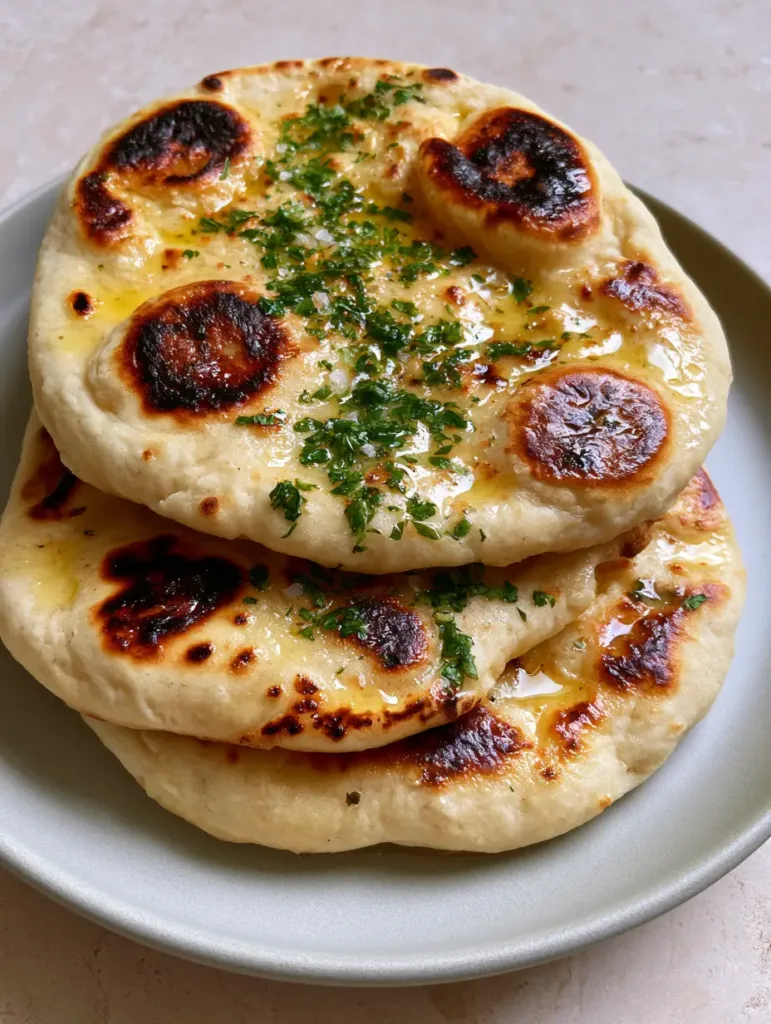 A top-down view of Sourdough Discard Naan topped with finely minced cilantro and flaky sea salt.