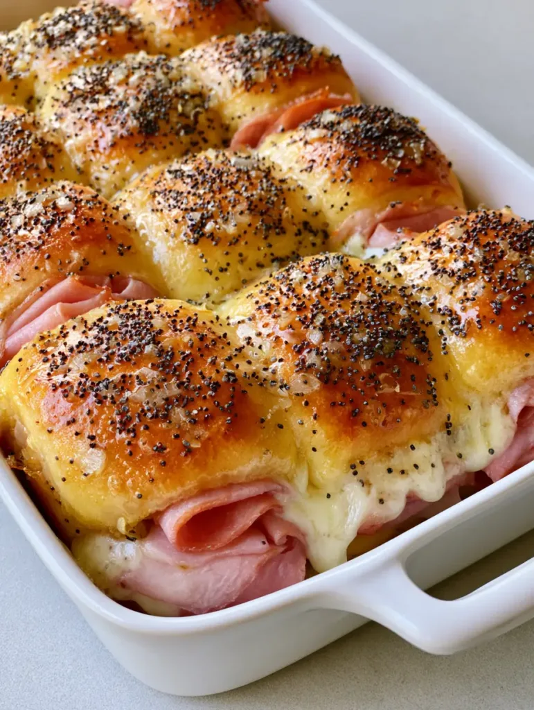 Hawaiian Ham and Cheese Sliders: The Ultimate Buttery Baked Party App 2 A smartphone-style photo of Hawaiian Ham and Cheese Sliders in a white dish, showing thick layers of ham and drooping melted cheese.
