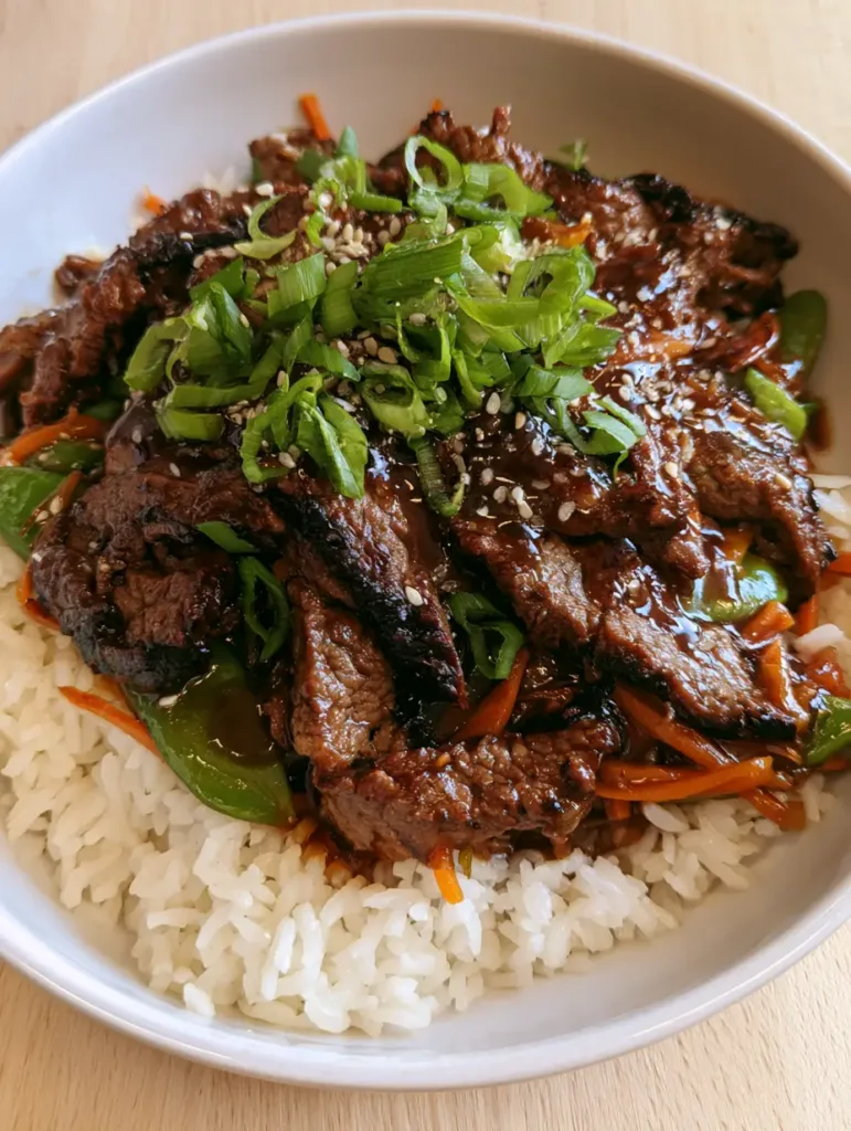 Top-down view of tender beef flank steak strips with dark seared edges and vibrant green snap peas. (Chinese Beef Recipe)