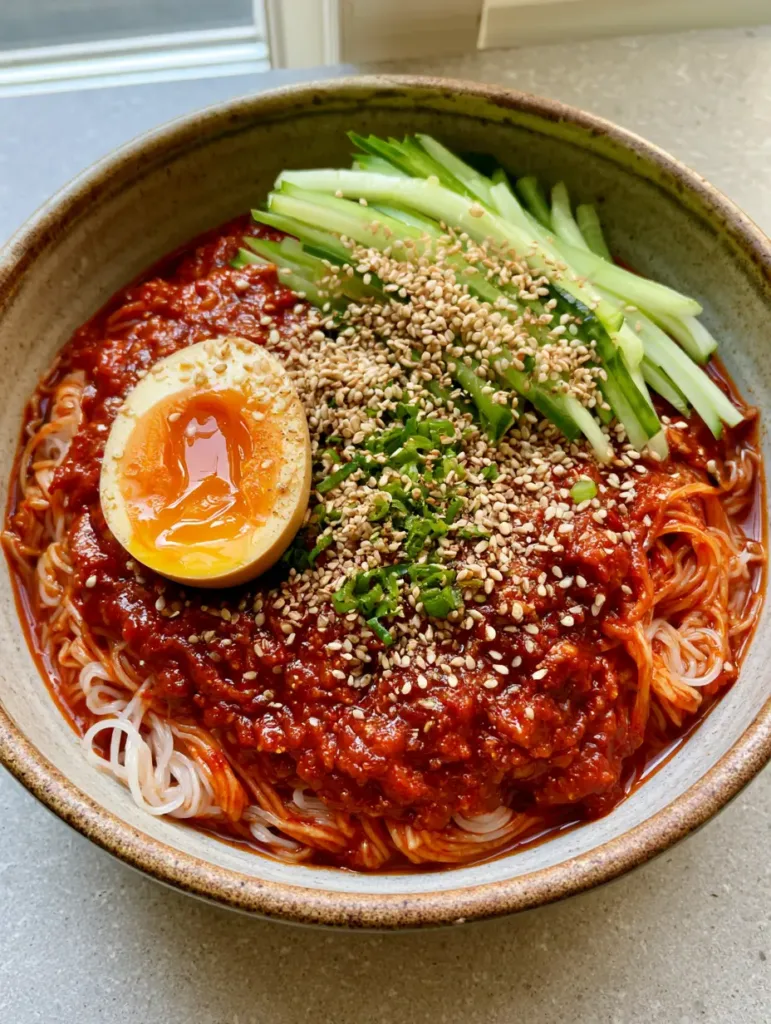 Bibim Guksu: The Ultimate Spicy Korean Cold Noodle Recipe 2 Overhead view of Korean spicy cold noodles with heavy sesame seed garnish and green scallions. (Bibim Guksu)