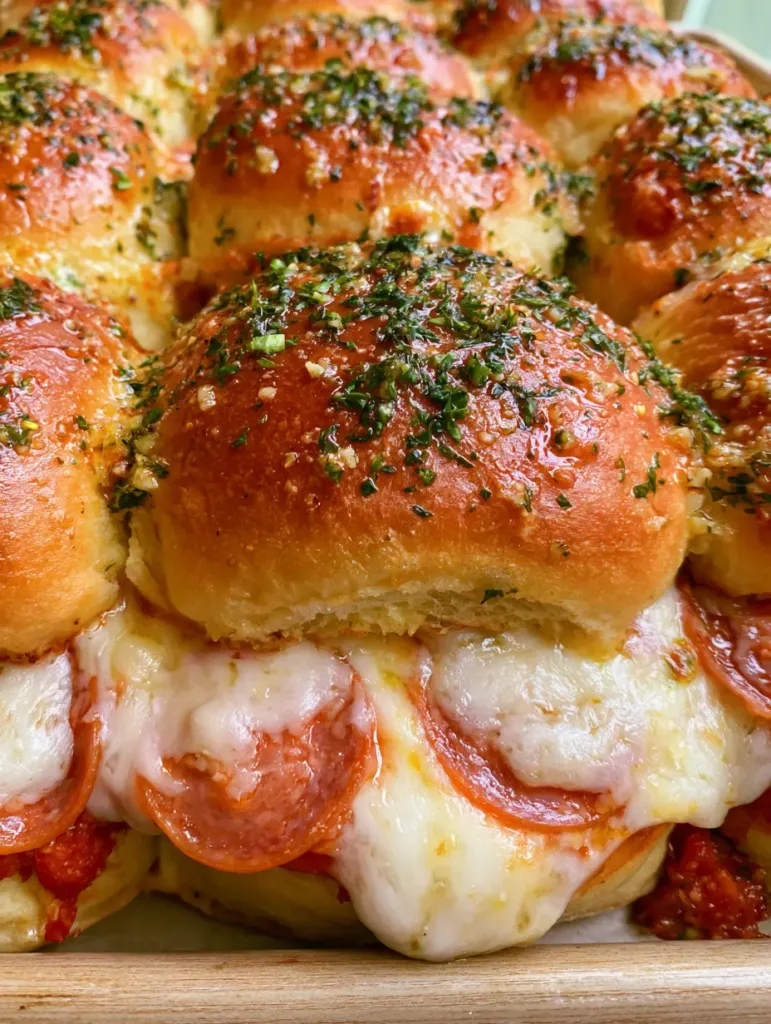 Hawaiian Roll Pizza Sliders: The Ultimate Gooey Garlic Butter Recipe 3 Handheld smartphone photo of warm Hawaiian Roll Pizza Sliders on a baking sheet, showing golden crust and parsley flakes.