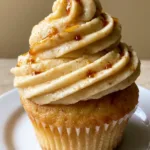Close-up of a vanilla cupcake topped with thick Maple Buttercream Frosting and amber drizzle.