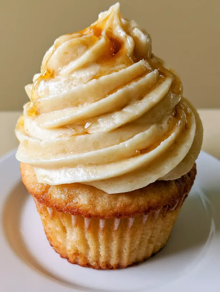 A handheld smartphone photo showing the texture of Maple Buttercream Frosting on a white plate.