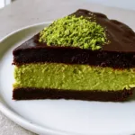 Eye-level photograph of a single slice of Dubai Chocolate Pistachio Tart on a white plate with visible layers.