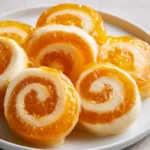 Creamsicle Vodka Jello Rollups: The Ultimate Boozy Nostalgic Treat Close up of Creamsicle Vodka Jello Rollups showing the translucent orange and opaque white layers.