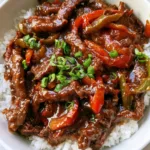 Close-up of Slow Cooker Pepper Steak in a white bowl showing the thick savory brown gravy and soft peppers. (Slow Cooker Pepper Steak)