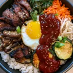 Smartphone photo of Bibimbap in a black bowl featuring seared zucchini, shiitake mushrooms, and gochujang sauce. (Bibimbap Recipe)
