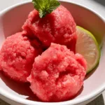 Watermelon Sorbet Recipe: The Ultimate Vibrant and Icy Summer Refreshment Close-up handheld smartphone photo of three scoops of vibrant pink watermelon sorbet in a matte white ceramic bowl with visible ice crystals. (Watermelon Sorbet Recipe)